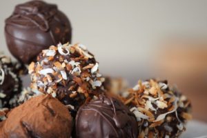 A close-up of assorted chocolate truffles with coconut and cocoa toppings.